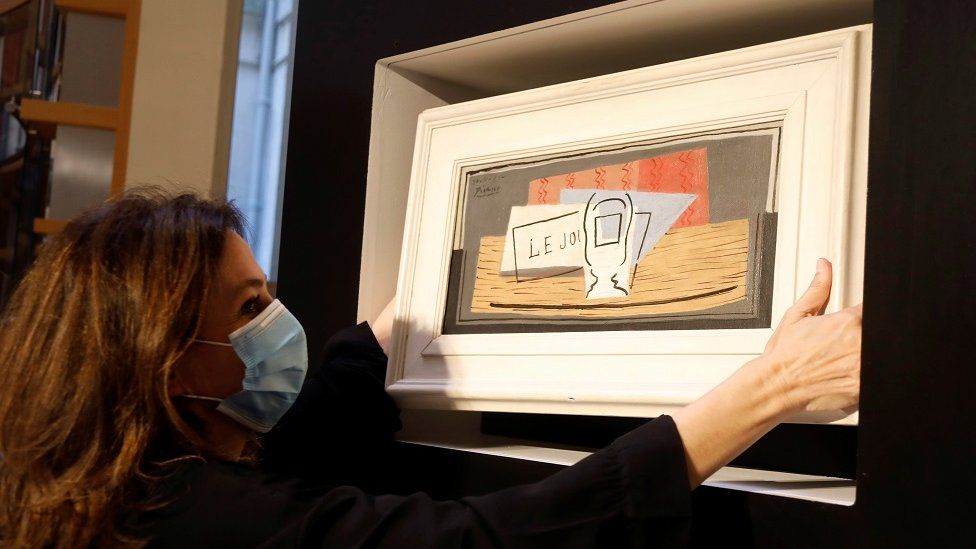 Raffle organizer Peri Cochin, wearing a protective face mask, poses with the Picasso's Nature Morte, during a charity raffle at Christie's auction house in Paris, 20 May 2020
