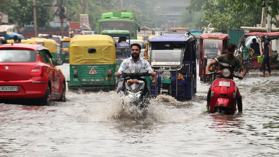 Motorcyclists ride through a flooded street after heavy rainfall at Jahangirpuri area in New Delhi.