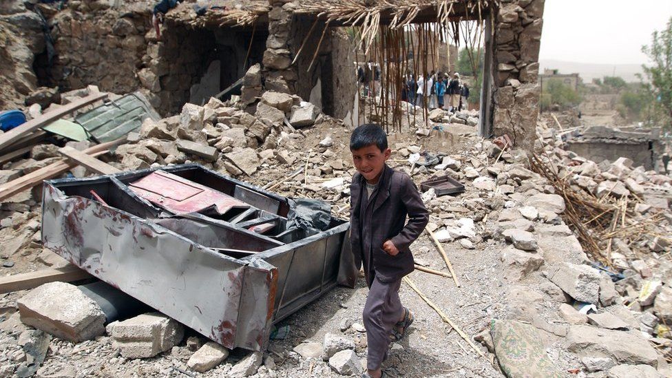 A young boy walking through rubble in Yemen
