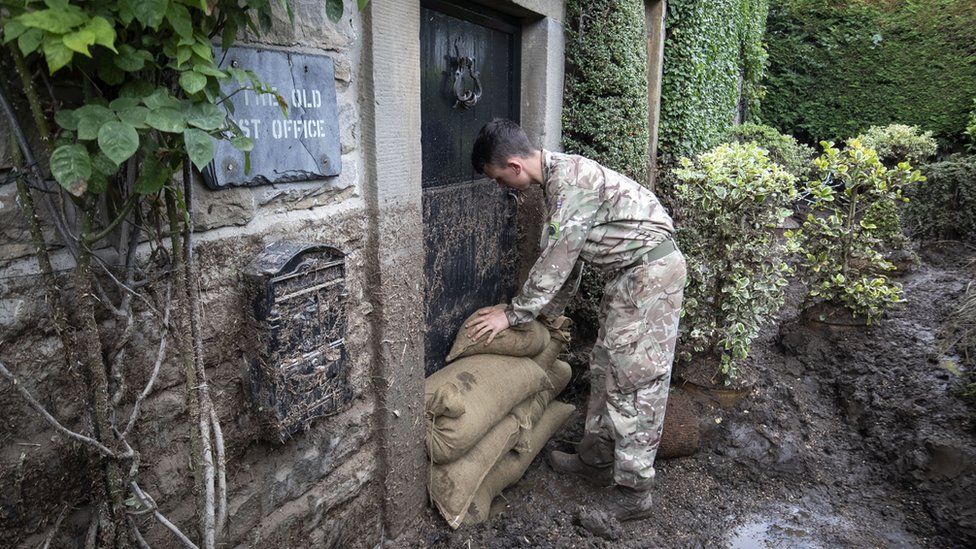 Soldier stacking sandbags in front of the old post office front door