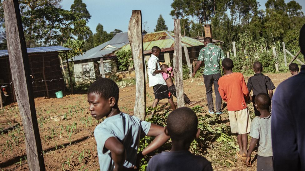 People look on as a girl knocked over by a bull is carried away in western Kenya