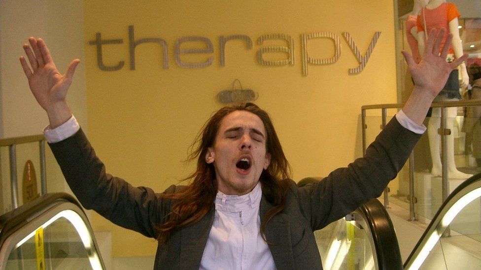 James Leadbitter standing in front of a 'therapy' sign