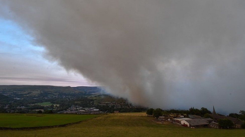 A large cloud of smoke covers the village of Mossley