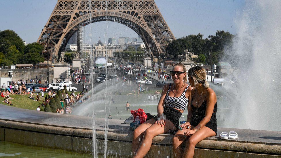 Women cool off at the Trocadero Fountains next to the Eiffel Tower in Paris