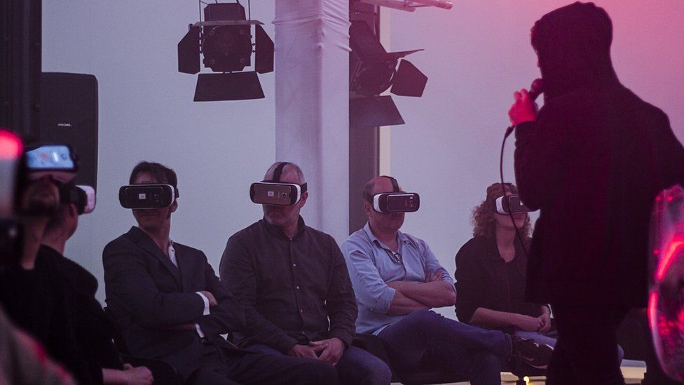 People listen to a singer while wearing virtual reality handsets