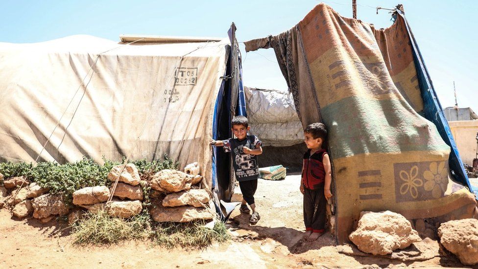 Сирийские дети сидят в лагере для перемещенных лиц в удерживаемой оппозицией провинции Идлиб, Сирия (6 июля 2023 г.)