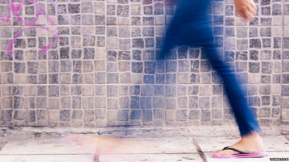 Blurry woman walking past wall