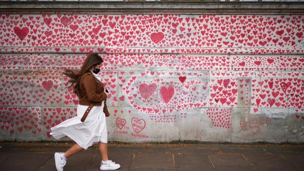 A woman walking past the national Covid memorial wall in London