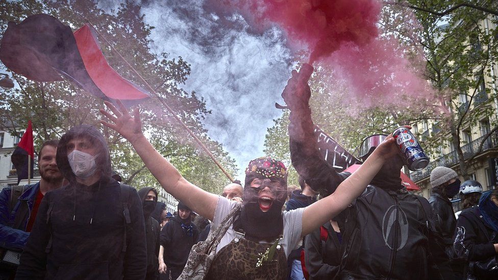 Protesters hold light flares and chant as they march through central Paris during a May Day rally in Paris, France.