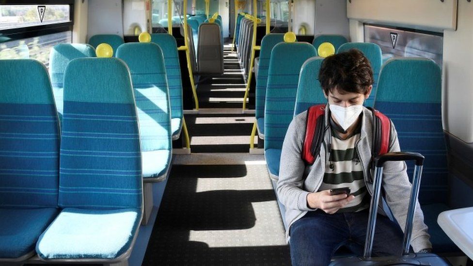 A man on a train with a mask on