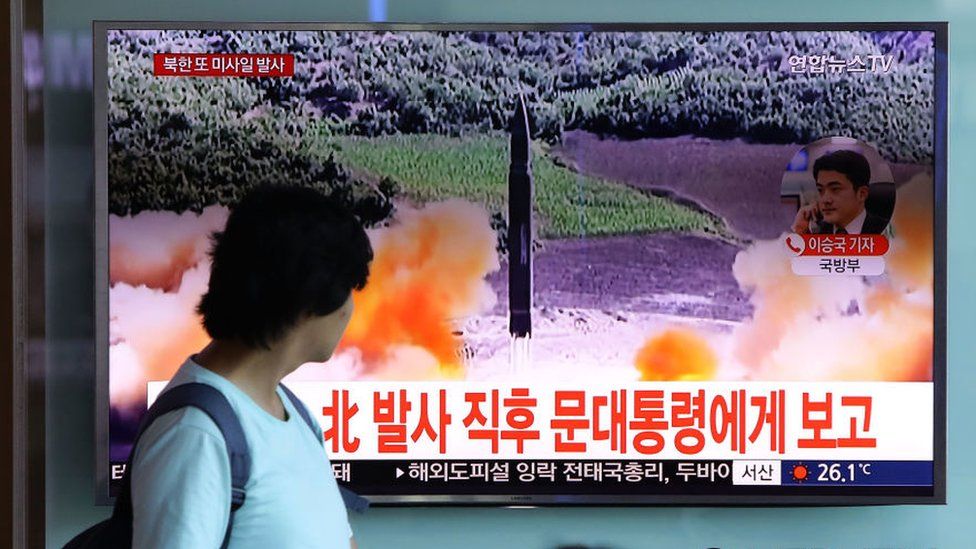 People watch a television broadcast reporting the North Korean missile launch