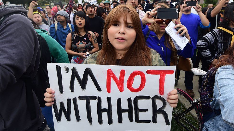 A woman holds an "I'm not with her" sign at an anti-Clinton protest in California