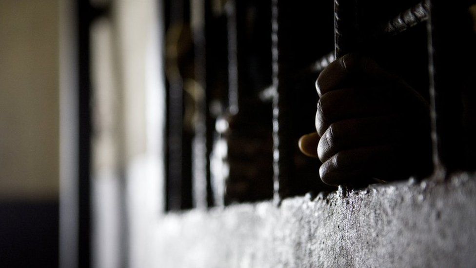 Prisoner's hands on the bars in his cell door, Liberia - 2011