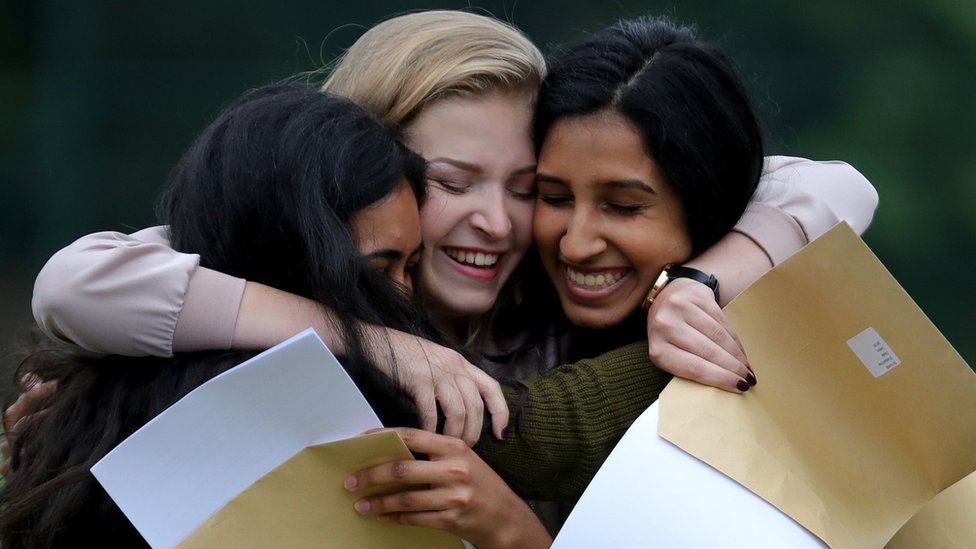 Three teenage girls hugging after getting their A level exam results