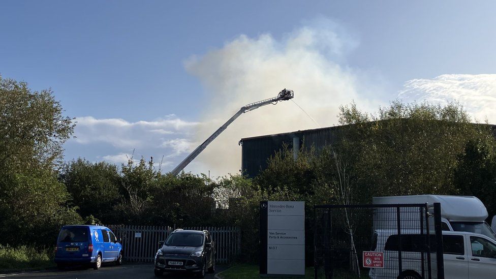 Firefighters on a crane trying to dampen down the fire at the factory site