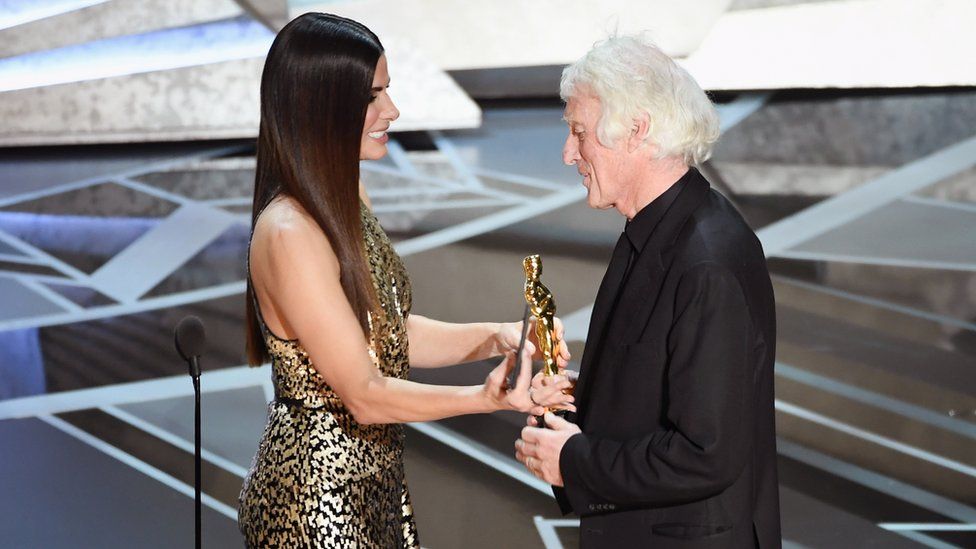 Cinematographer Roger A. Deakins (R) accepts Best Cinematography for 'Blade Runner 2049' from actor Sandra Bullock onstage during the 90th Annual Academy Awards