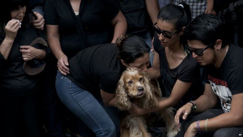 Family and friends embrace Cosmos, the dog of murdered photojournalist Ruben Espinosa during his funeral service in Mexico City on 3 August, 2015.