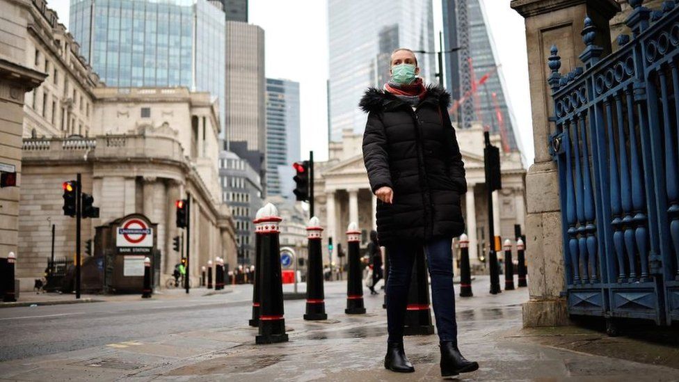 Женщина гуляет по городу в маске.