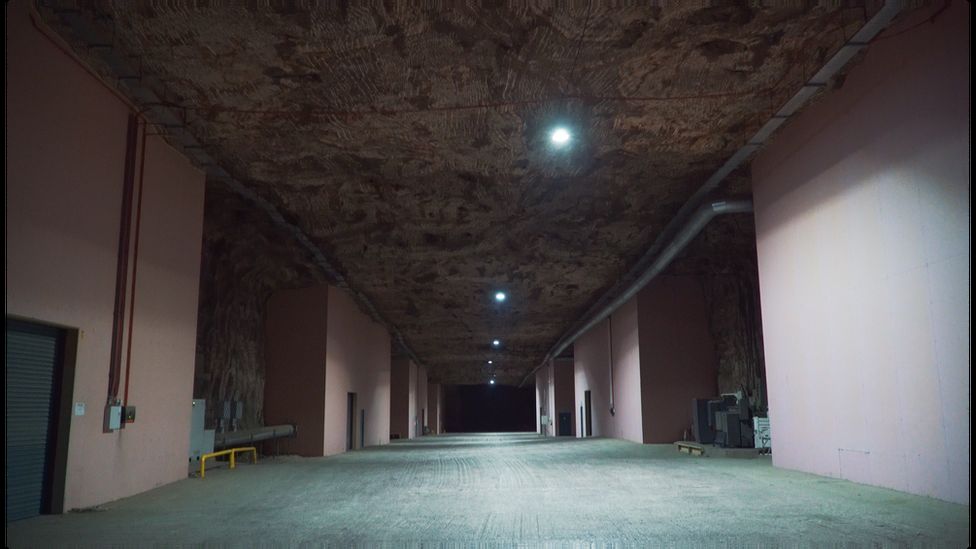 Un buio e ampio corridoio vuoto nel sottosuolo con magazzini allineati