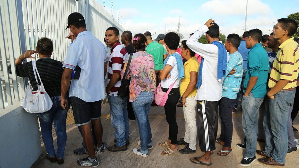 Venezuelans queue outside the federal police station in Boa Vista