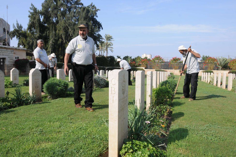 Members of the Jaradah family work to tend the laws and flowers at the cemetery in Gaza.