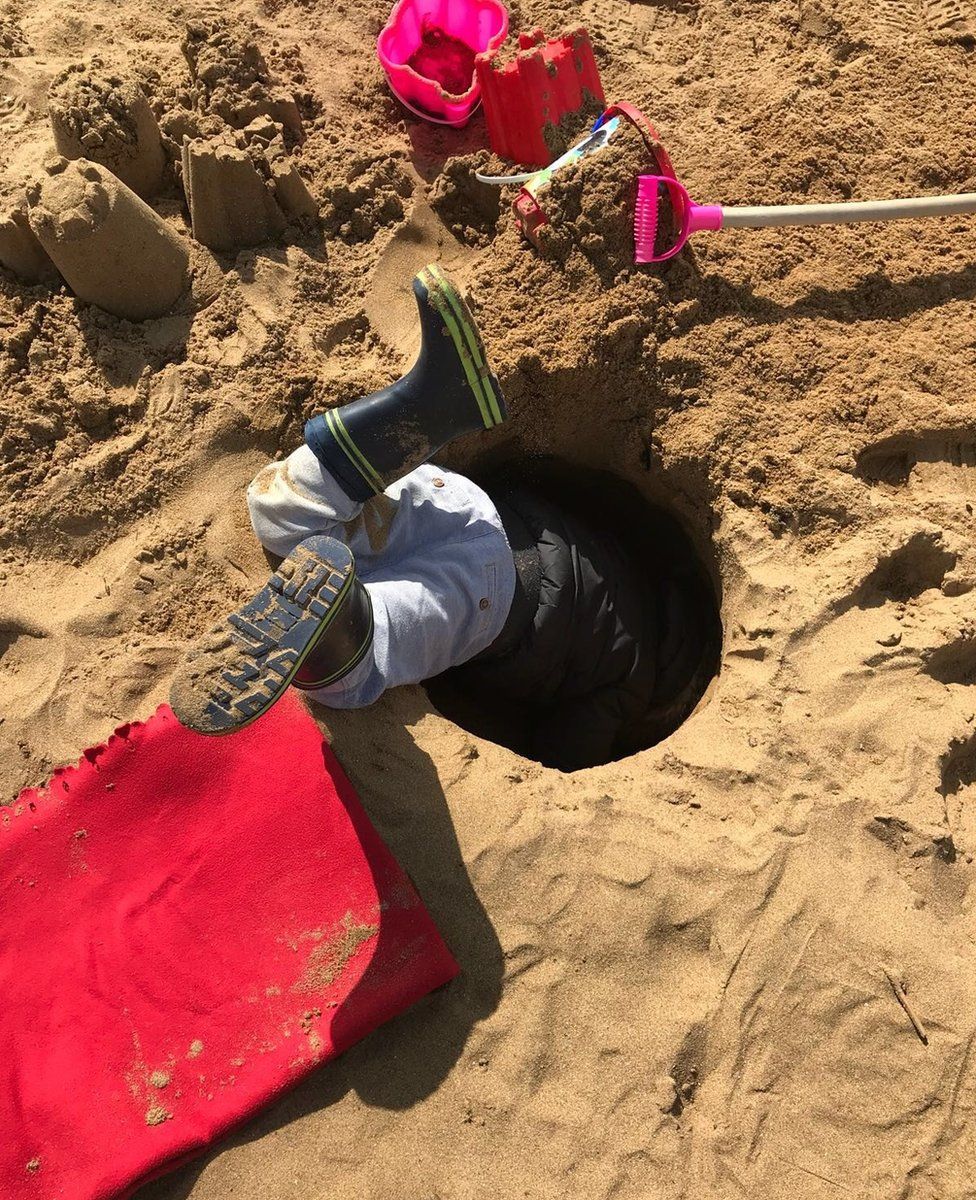 Boy in a hole on the beach