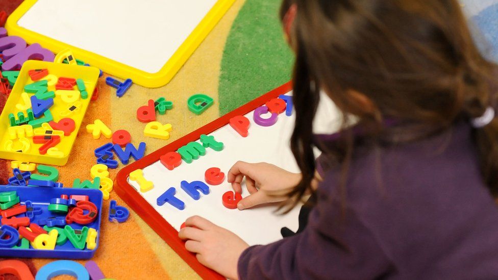 Child placing coloured letters on a whiteboard