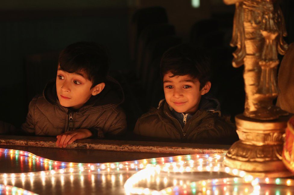 Young boys look at a light installation as people gather to celebrate the Hindu festival of Diwali