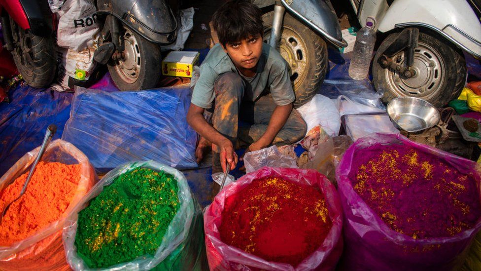 A boy selling colored powder or Gulal at a market, ahead of Holi Festival in Guwahati, Assam, India on 6 March 2023. Holi is a celebration of the divine love between Lord Krishna and Radha and the victory of good over evil.
