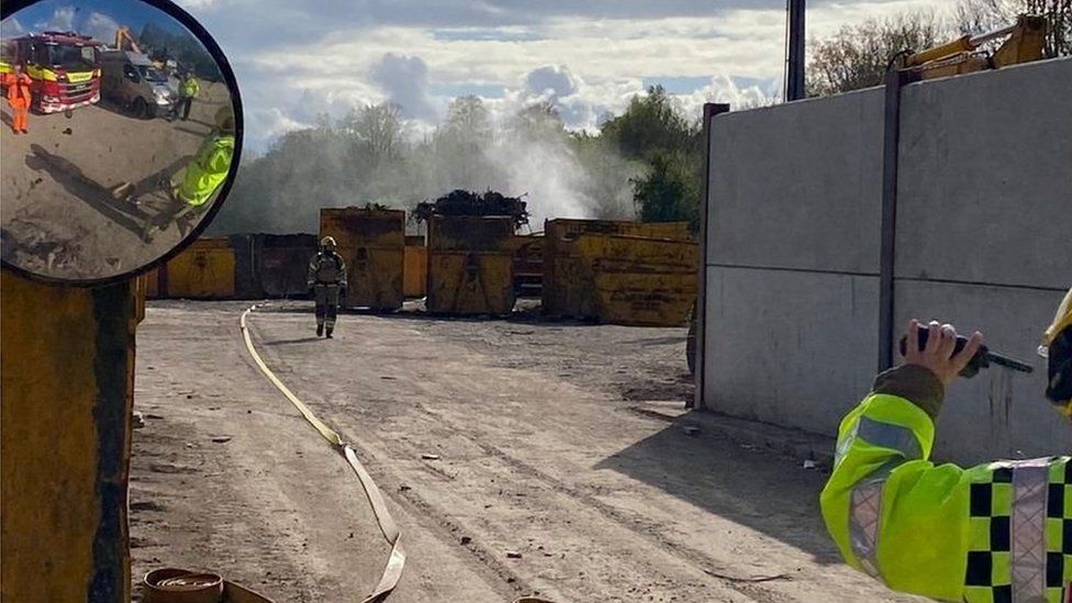 A firefighter walking with smoke behind him