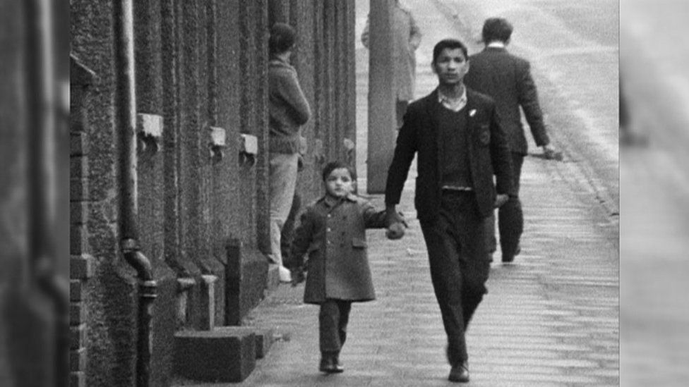 An Asian man and boy walking down a street