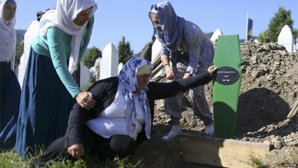 An elderly woman is comforted as she cries at an open grave in Memorial Centre in Potocari, near Srebrenica.