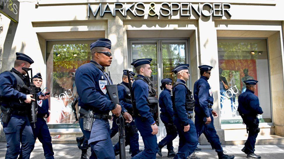 French police walk past Marks & Spencer, 21 April, where their fallen colleague was shot on the Champs Elysees in Paris