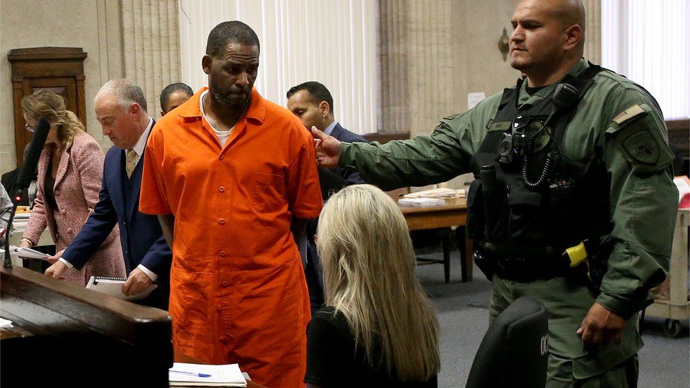 R. Kelly wearing an orange jump suit being led away by a guard in court in Chicago in September 2019