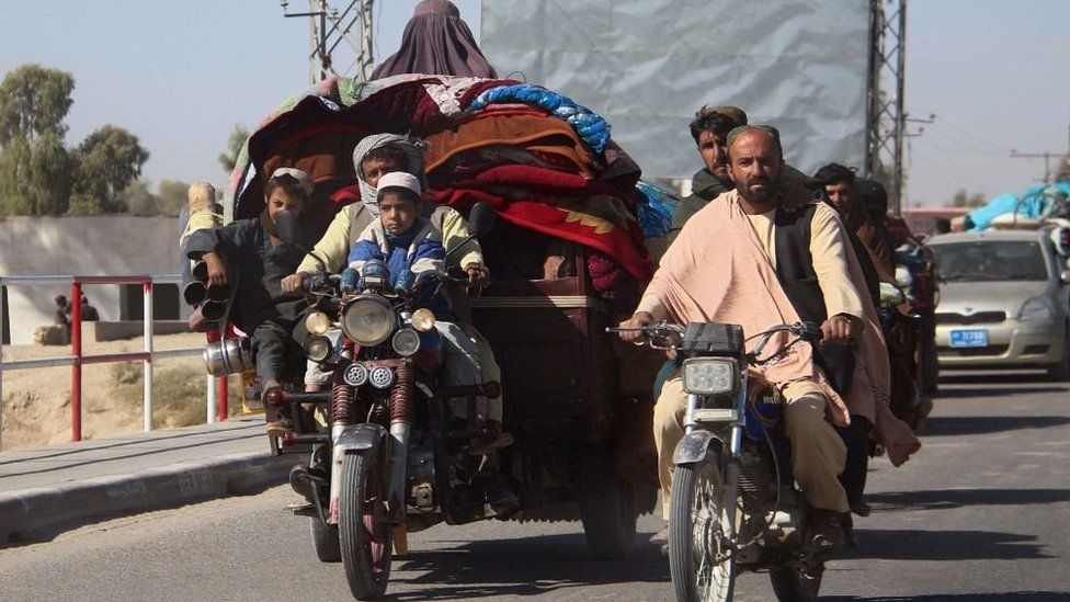 People on motorised vehicles heavily laden with carpets and blankets