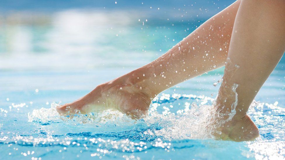 Woman's feet above surface of swimming pool