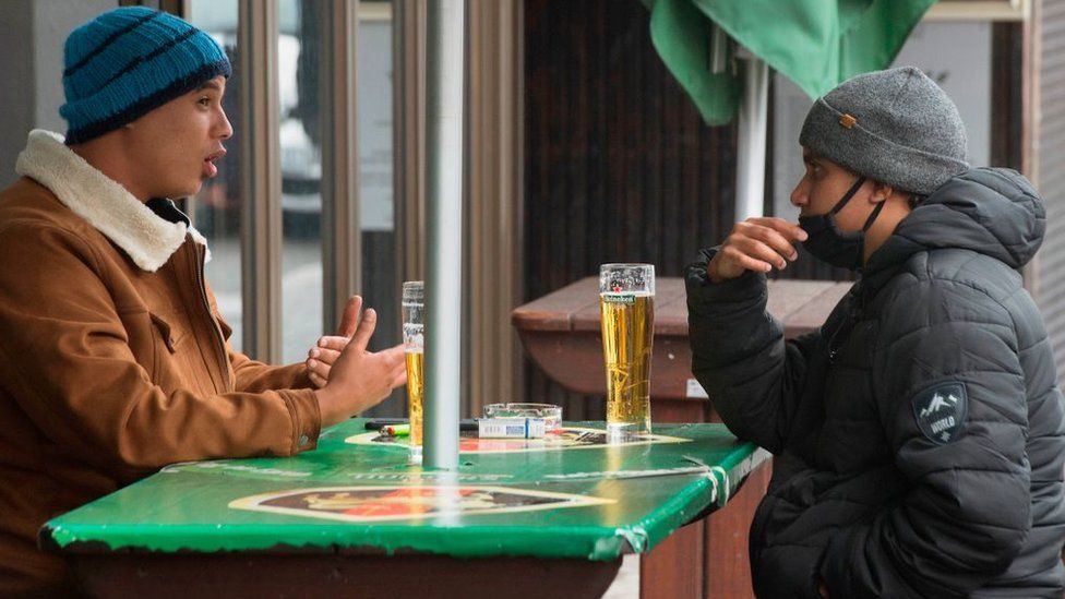 Two men enjoy some beers at a streetside bar in the city centre in Cape Town, on August 18, 2020.