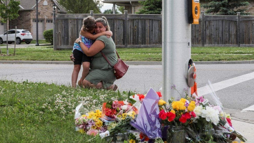 Люди реагируют возле цветов, возложенных на месте преступления в Лондоне, Онтарио, Канада, 7 июня 2021 года.
