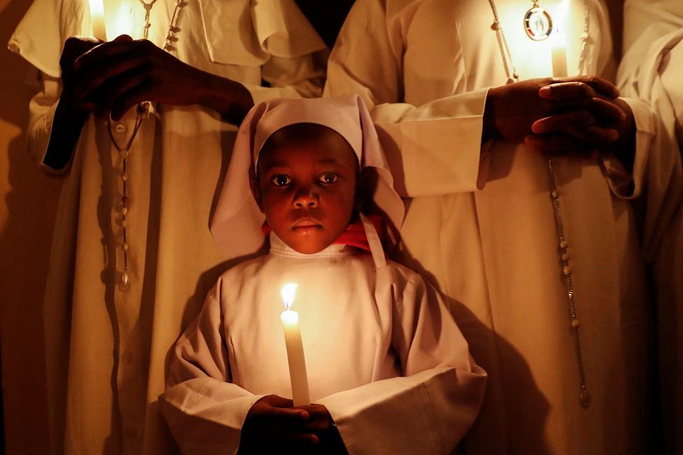 Worshipers hold candles during Easter vigil prayers at the St. Joanes, Legio Maria of African Church Mission within Fort Jesus in Kibera district of Nairobi.