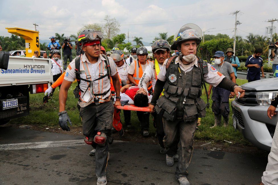 Firefighters carry a man on a stretcher near an area affected by the eruption