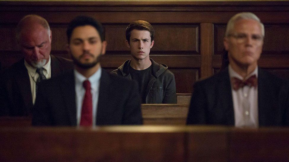 Main character Clay Jensen sits in a courtroom