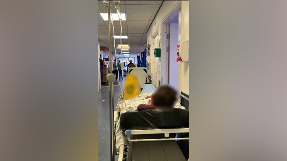 A patient on a trolley in a hospital corridor