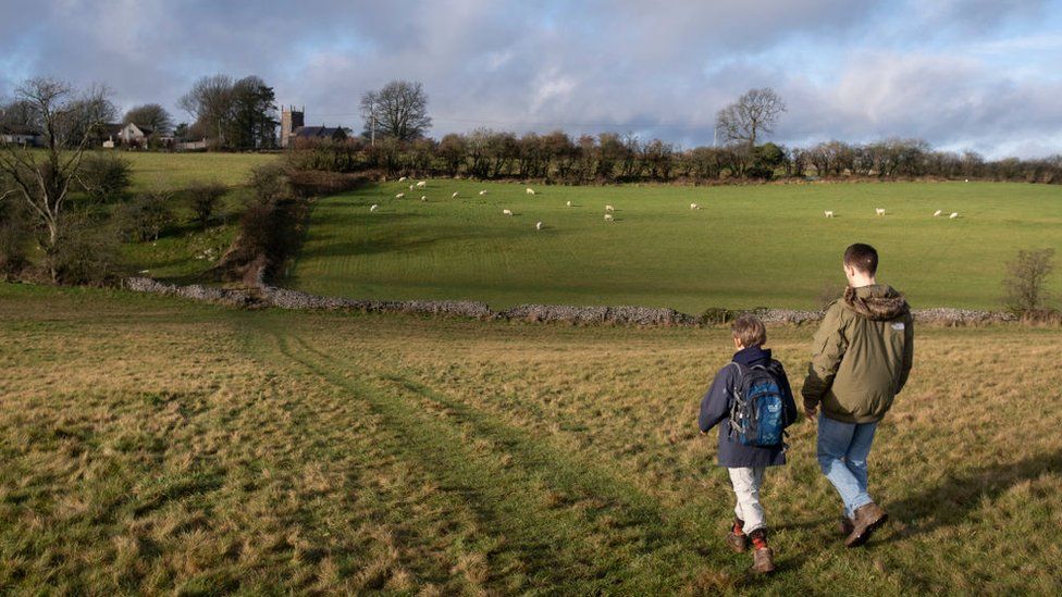 A boy and a man walk on a path through a field in Somerset