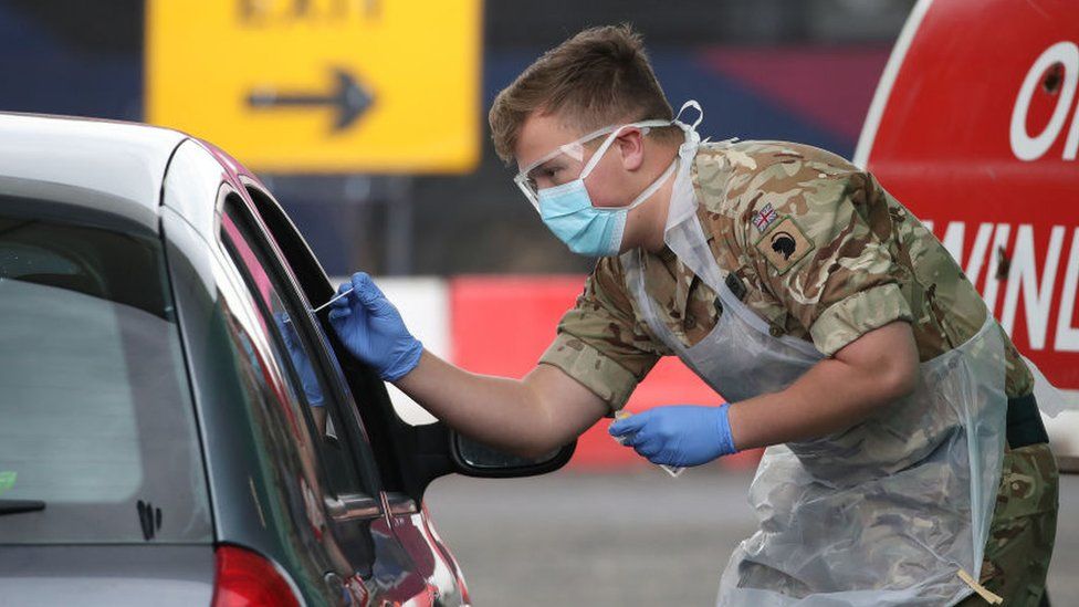 Солдат из 2-го шотландского королевского полка Шотландии берет образец для испытаний в центре тестирования Covid-19 в аэропорту Глазго в апреле 2020 г.