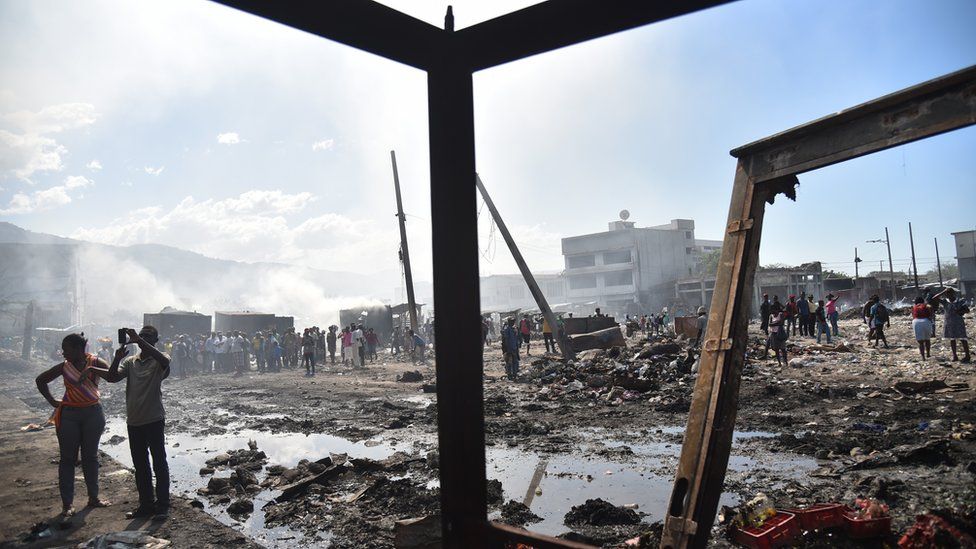 Citizens stand amid the burnt-out wreckage of the Iron Market.