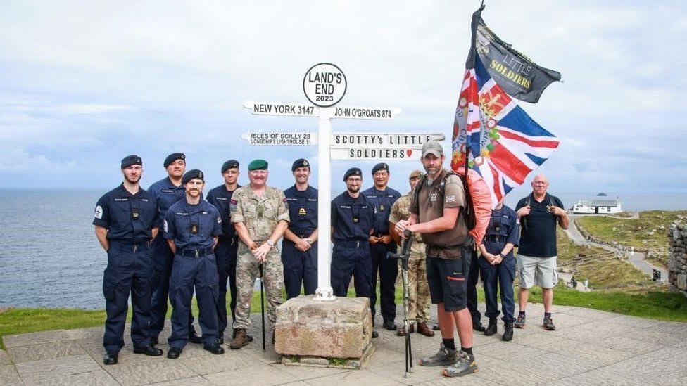 Mark with a group of people in military uniforms at the Land's End sign