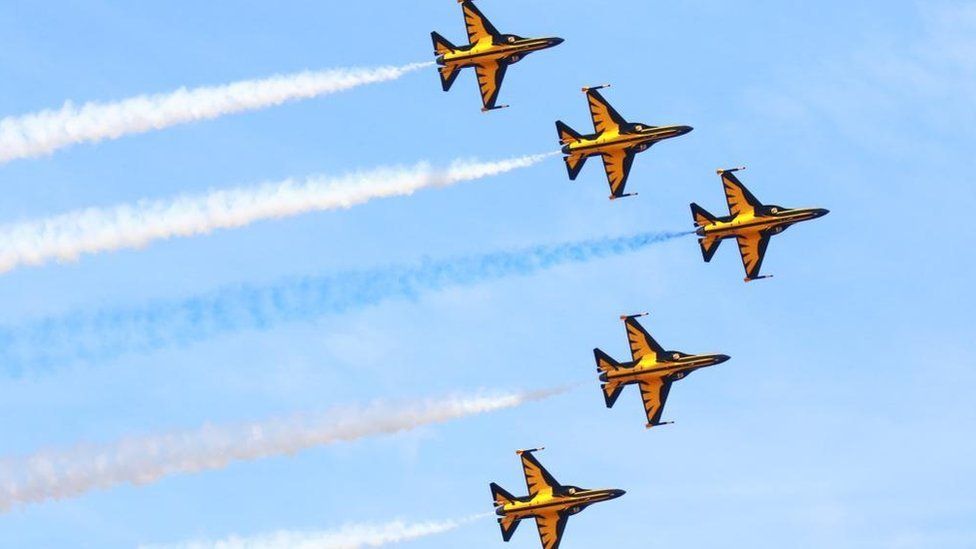Five black and yellow planes in an arrow formation