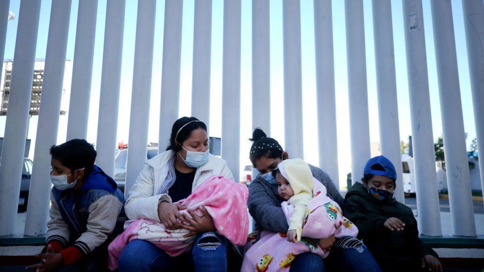 Граждане Сальвадора и Гондураса, ищущие убежища в Соединенных Штатах, сидят у пограничного перехода Эль-Чапараль 19 февраля 2021 года в Тихуане, Мексика