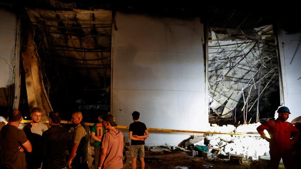 People gather at the site following a fatal fire at a wedding celebration