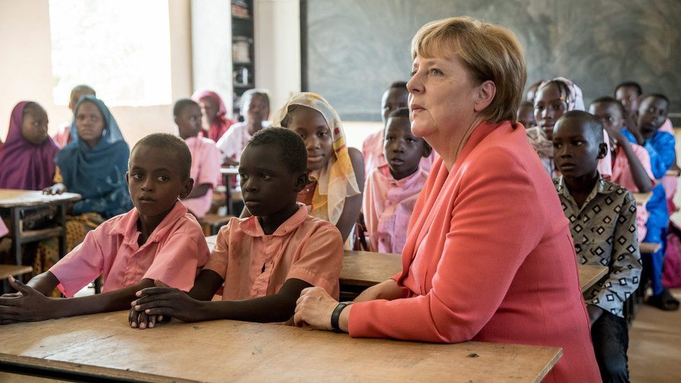German Chancellor Angela Merkel (R) speaks with primary school students from the Goudell II. school in Niamey, Niger, on 10 October 2016